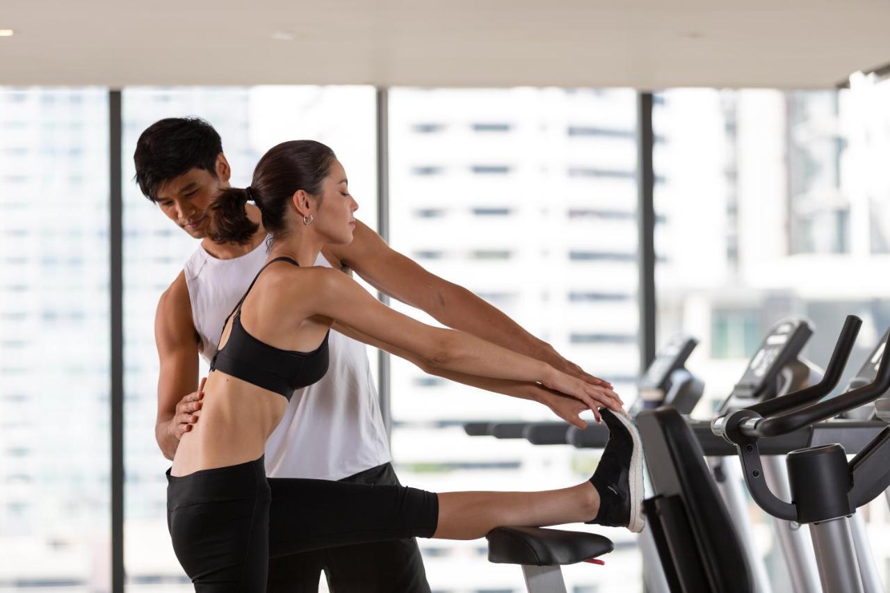Ascott Thonglor Bangkok Hotell Exteriör bild A personal trainer assisting a woman with a stretching exercise